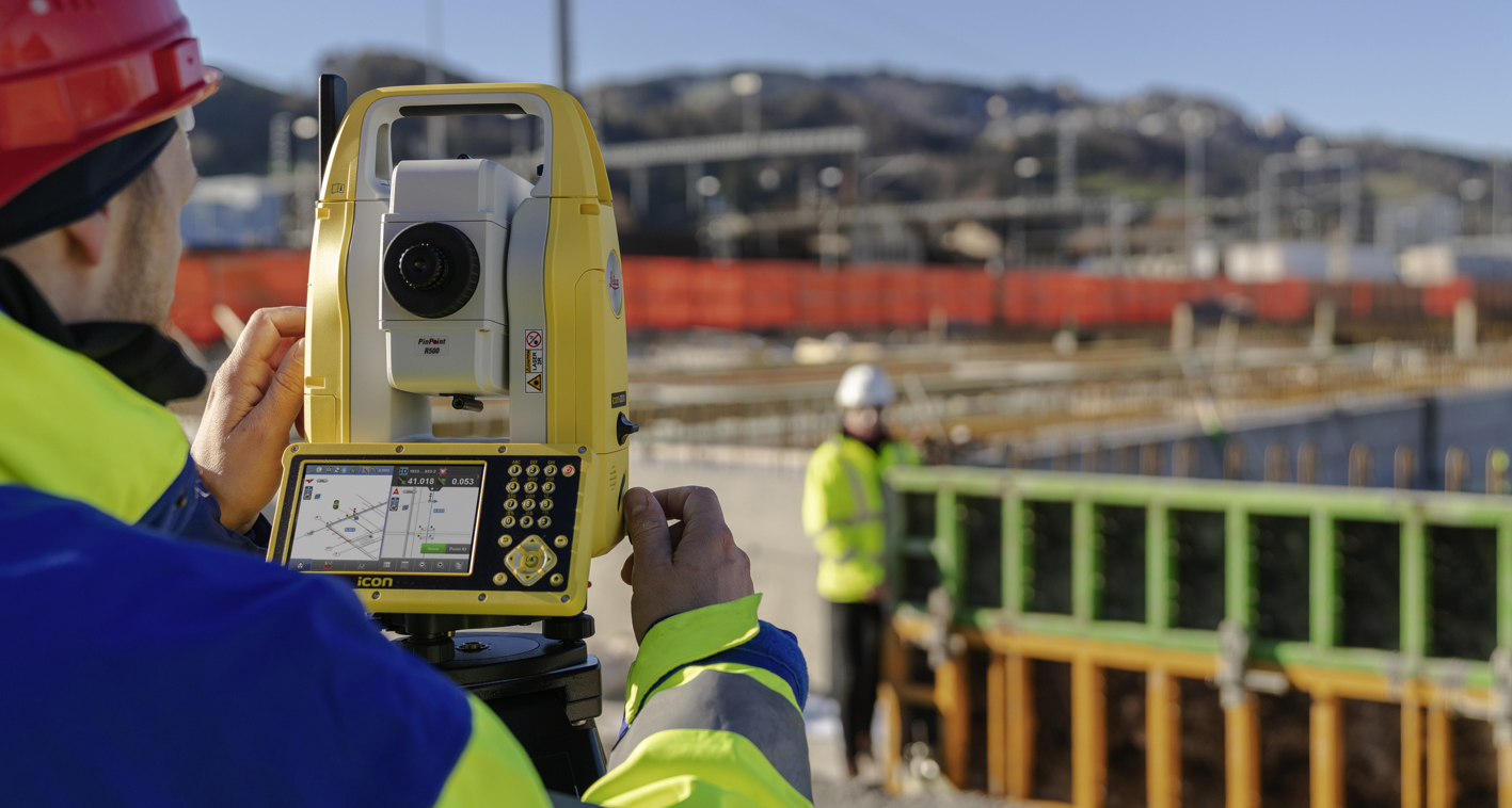 Construction worker using a Leica iCON manual total station to lay out  points on a construction site.